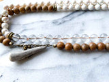 closeup of gemstone bead necklace comprising white pearl, white bone, natural quartz and exotic wood with antler clasp