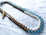 top view of gemstone bead necklace comprising white pearl, blue aquamarine and exotic wood with antler clasp