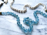 closeup of gemstone bead necklace comprising white pearl, blue aquamarine and exotic wood with antler clasp