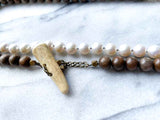 closeup of gemstone bead necklace comprising white pearl, blue aquamarine and exotic wood with antler clasp