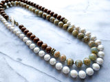 top view of gemstone bead necklace comprising white pearl, neutral calcite and exotic wood with antler clasp