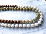 side view of gemstone bead necklace comprising white pearl, neutral calcite and exotic wood with antler clasp