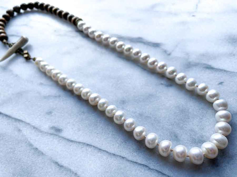 top view of gemstone bead necklace comprising white pearl and exotic wood with antler clasp