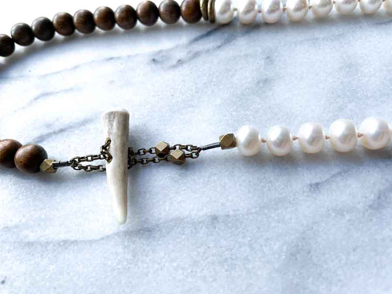 closeup of gemstone bead necklace comprising white pearl and exotic wood with antler clasp