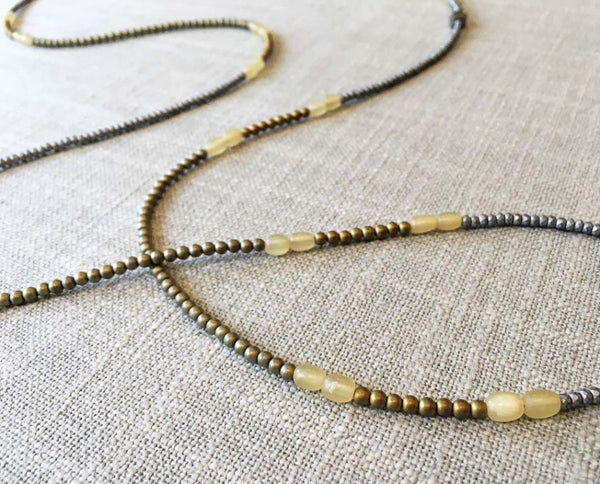 closeup of gemstone bead necklace comprising light yellow horn, gold hematite and silver hematite