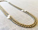 top view of gemstone bead necklace comprising carved white shell, matte gold and golden pyrite