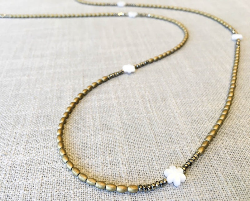 closeup of gemstone bead necklace comprising carved white shell, gold hematite and golden pyrite