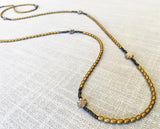 closeup of gemstone bead necklace comprising carved tahitian shell, gold hematite and dark bronze