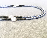 side view of gemstone bead necklace comprising carved white shell, silver hematite and pyrite