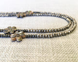 side view of gemstone bead necklace comprising carved golden shell, silver-plate pyrite and dark grey raw pyrite