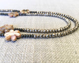 side view of gemstone bead necklace comprising tan carved tahitian shell, silver-plate pyrite and dark grey raw pyrite