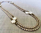 top view of gemstone bead necklace comprising carved shell, cream pearl and gold hematite