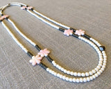 top view of gemstone bead necklace comprising carved pink shell, white conch shell and dark grey pyrite