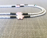 side view of gemstone bead necklace comprising carved pink shell, white conch shell and dark grey pyrite