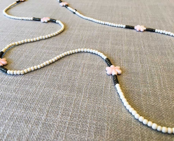 closeup of gemstone bead necklace comprising carved pink shell, white conch shell and dark grey pyrite