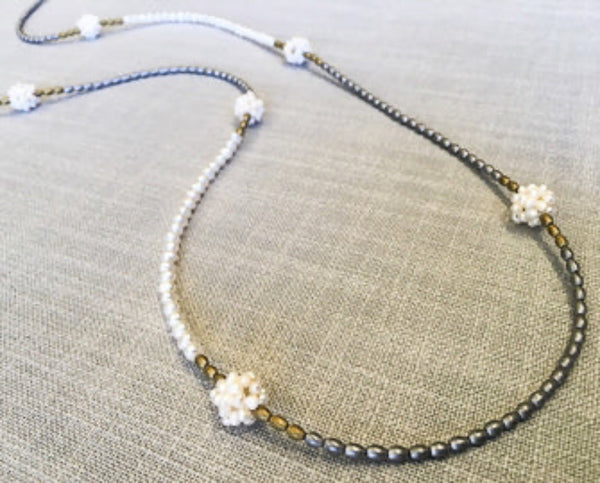 closeup of gemstone bead necklace comprising hand sewn white pearl balls, matte gold and matte silver