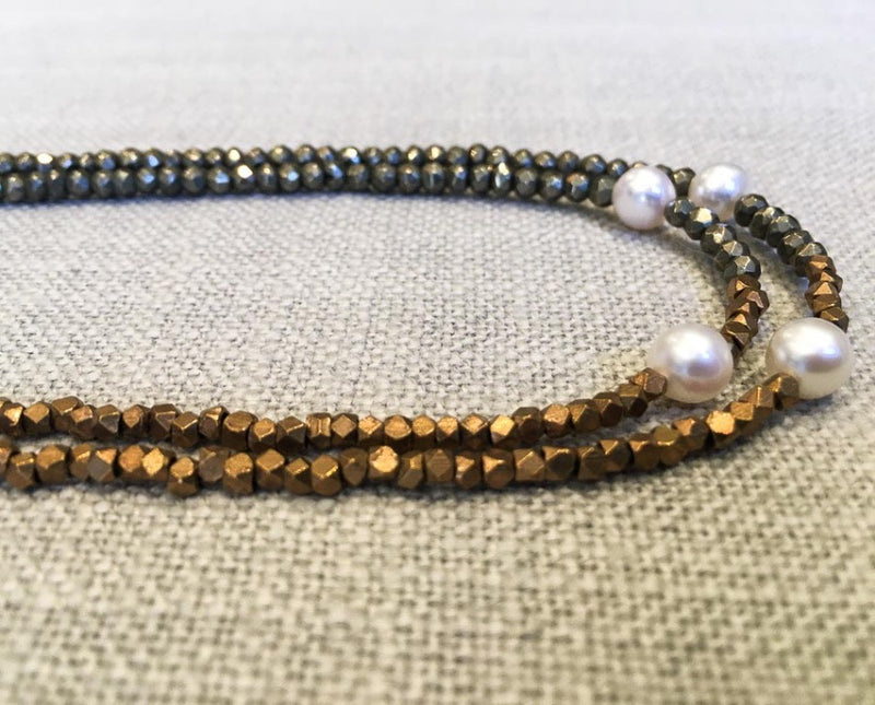 side view  of gemstone bead necklace comprising white pearl, bronze and dark grey pyrite