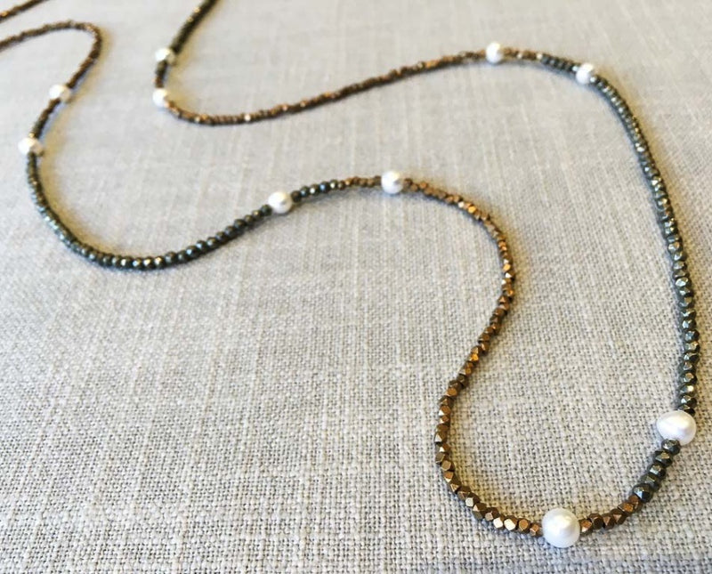 closeup of gemstone bead necklace comprising white pearl, bronze and dark grey pyrite