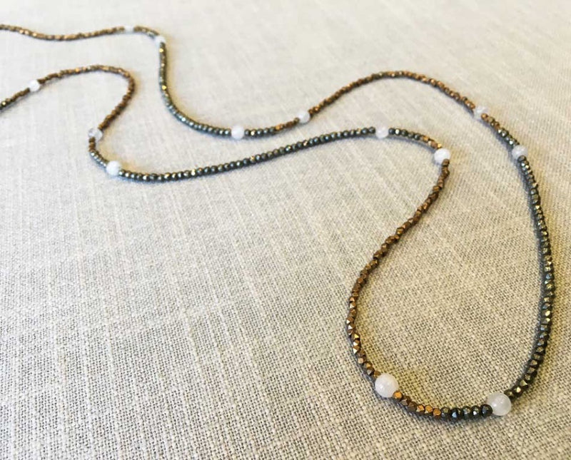 closeup of gemstone bead necklace comprising white moonstone, bronze and dark grey pyrite