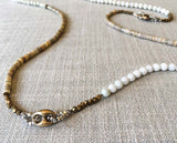 closeup of gemstone bead necklace comprising white moonstone, tan shell and bronze mariners link