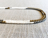 side view of gemstone bead necklace comprising gold hematite and white shell