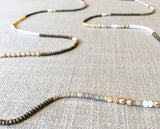 closeup of gemstone bead necklace comprising cream pearl, beige shell and light gold hematite