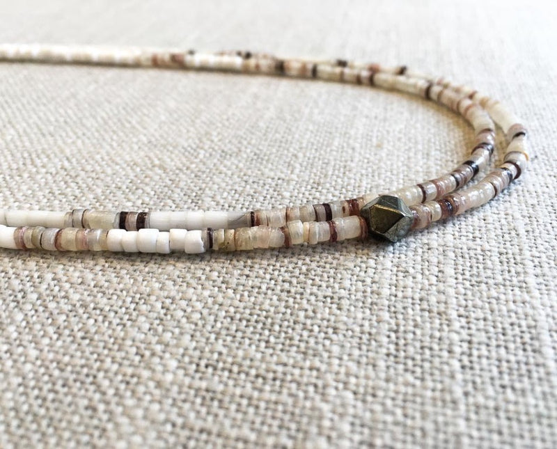 side view  of gemstone bead necklace comprising white shell 