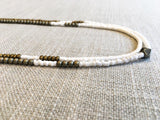 side view  of gemstone bead necklace comprising white shell and gold hematite