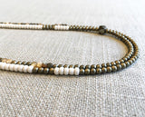 side view  of gemstone bead necklace comprising tan shell, white horn and matte light gold