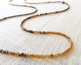 closeup of gemstone bead necklace comprising tan shell, white horn and light gold hematite