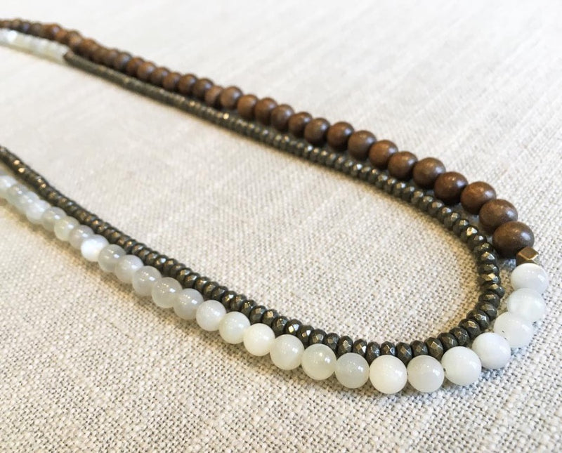 top view of gemstone bead necklace comprising white moonstone, dark grey pyrite and exotic wood