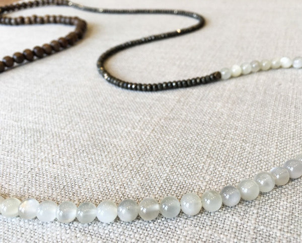 closeup of gemstone bead necklace comprising white moonstone, dark grey pyrite and exotic wood