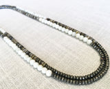 top view of gemstone bead necklace comprising white siberian moonstone, neutral shell and dark grey pyrite