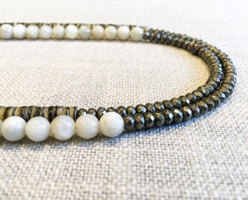 side view  of gemstone bead necklace comprising white siberian moonstone, neutral shell and dark grey pyrite