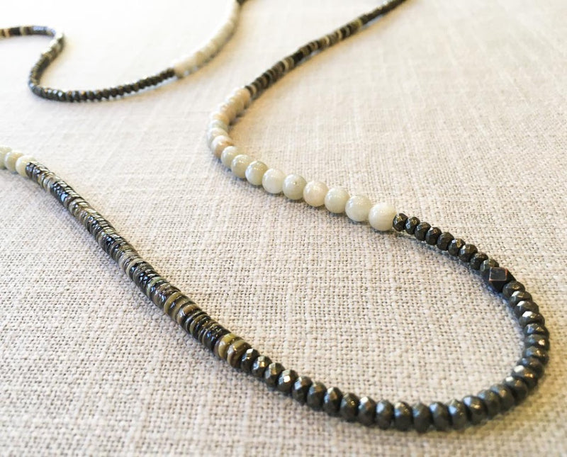 closeup of gemstone bead necklace comprising white siberian moonstone, neutral shell and dark grey pyrite