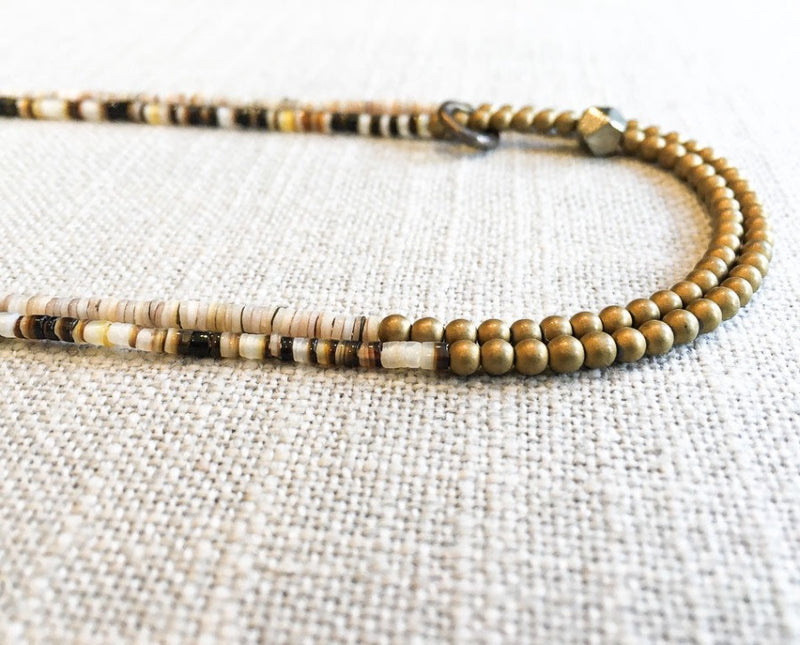 side view of gemstone bead necklace comprising neutral shell and matte gold