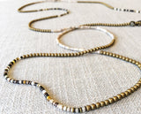 closeup of gemstone bead necklace comprising neutral shell and gold hematite