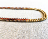 side view of gemstone bead necklace comprising pink garnet, matte bronze and matte gold