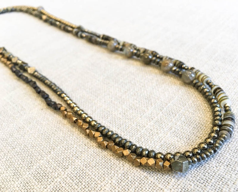 top view of gemstone bead necklace comprising green labradorite, dark grey pyrite. neutral shell and bronze