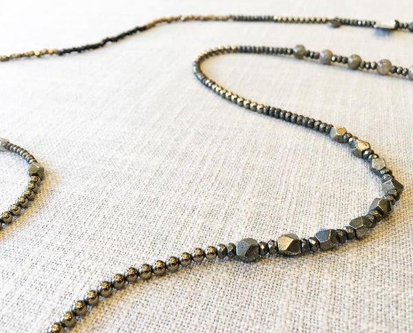 closeup of gemstone bead necklace comprising green labradorite, dark grey pyrite, neutral shell and bronze