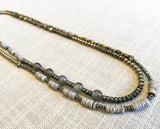 top view of gemstone bead necklace comprising grey moonstone, dark grey pyrite, grey shell and bronze