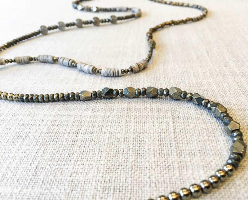 closeup of gemstone bead necklace comprising grey moonstone, dark grey pyrite, grey shell and bronze