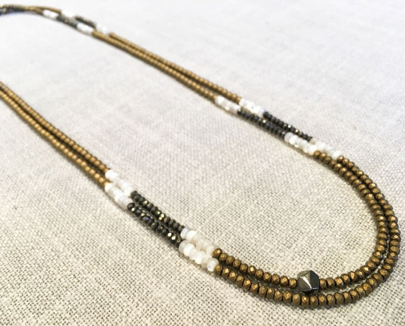  top view of gemstone bead necklace comprising dark grey pyrite, white shell and gold hematite