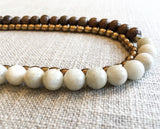 side view of gemstone bead necklace comprising off-white siberian moonstone, exotic wood and bronze