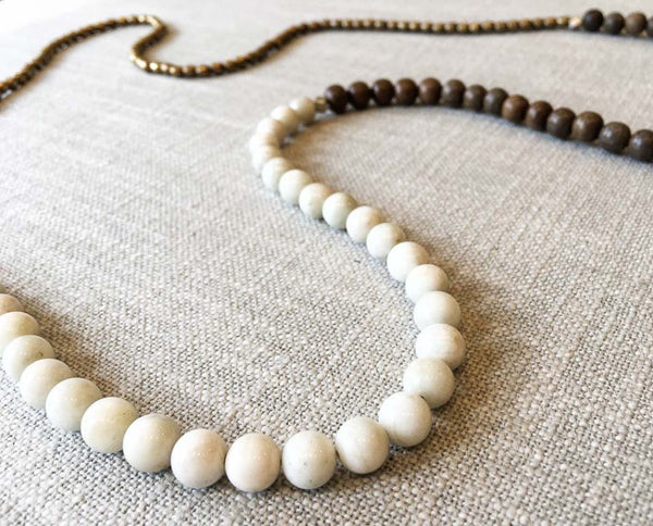 closeup of gemstone bead necklace comprising off-white siberian moonstone, exotic wood and bronze