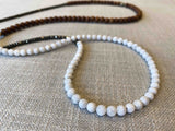 closeup of gemstone bead necklace comprising white moonstone, exotic wood and dark grey pyrite  Edit alt text