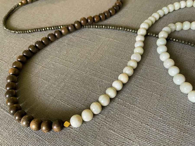 closeup of gemstone bead necklace comprising white moonstone, dark grey pyrite and exotic wood