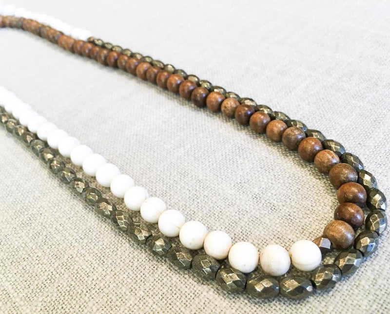 top view of gemstone bead necklace comprising off-white antique bone, dark grey pyrite and exotic wood