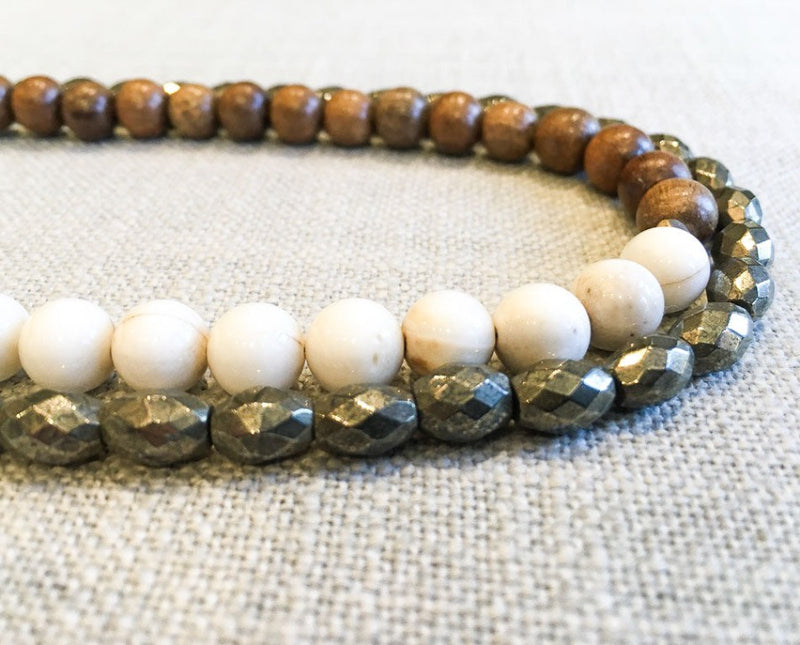 side view of gemstone bead necklace comprising off-white antique bone, metallics and exotic wood