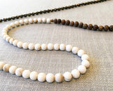 closeup of gemstone bead necklace comprising off-white antique bone, dark grey pyrite and exotic wood